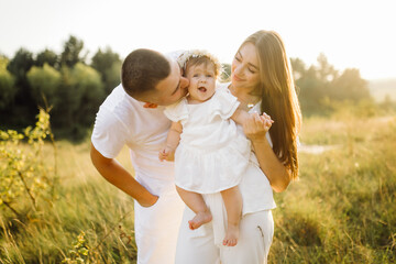 Fototapeta premium Young family with cute little daughter walking in forest on the sunset
