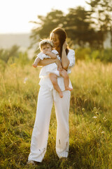 Young family with cute little daughter walking in forest on the sunset