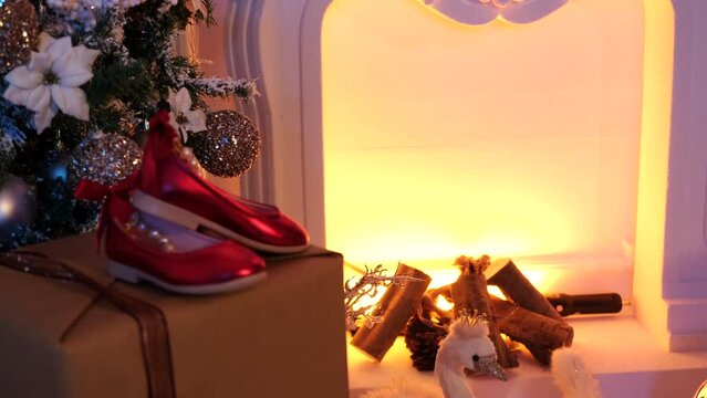 Close up footage of gift boxes and some christmas ornaments in front of a fireplace.
