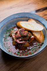 baked octopus with potatoes in sauce with crispy bread