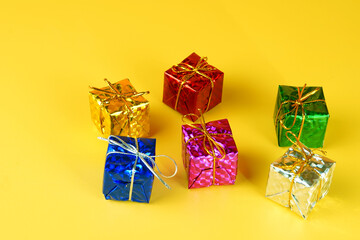 Metallic colorful presents with gold strings isolated on yellow