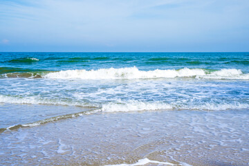 Light blue sea waves on a clean sandy beach..
