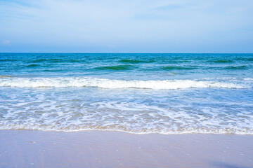 Light blue sea waves on a clean sandy beach..
