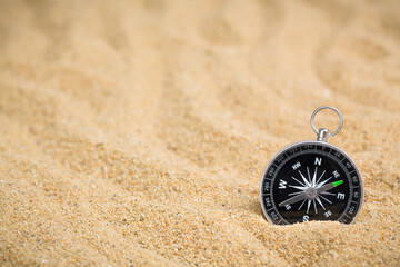 Compass in the sea sand on beach background with copy space for add text message or use components for design. Summer Travel destination and Navigation Concept Backdrop.