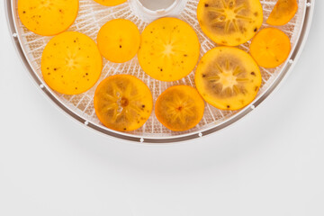 fresh persimmon pieces in a drying tray, top view