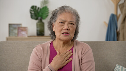 webcam view of an asian Japanese senior female patient waving hi and telling online doctor about her head and heart disease while having virtual consultation at home