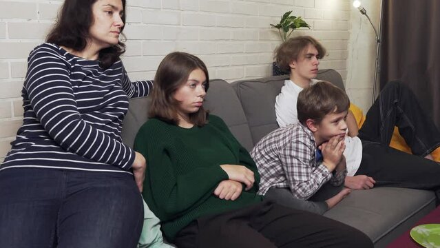 mother and three children, sitting on the sofa, watching TV