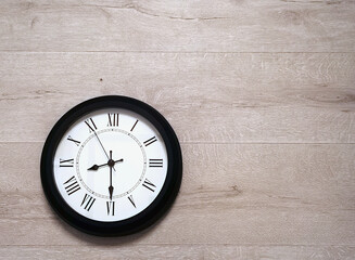 A round wall clock hanging on a wooden wall.