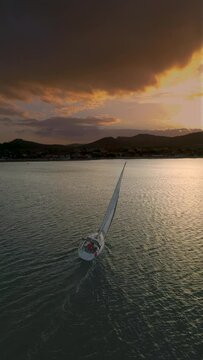 Aerial view of the Medium sized Yacht in the bay during sunset. Romantic sunset at the sea. Yacht sailing on open sea at sunset . Sailing aerial 4k video footage. High quality 4k footage