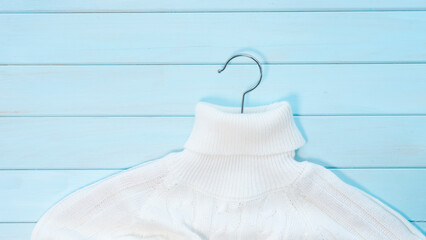 White knitted sweater on a light blue wooden background