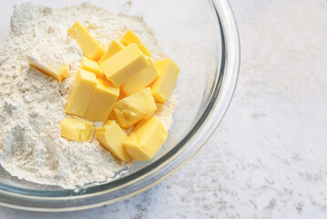 cold butter cube with flour in a glass bowl on marble background