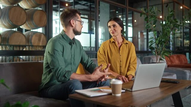 Portrait of pretty successful young woman and attractive bearded man discussing talking about work using laptop smiling looking at camera. Elegant stylish modern colleagues. Job interview concept.