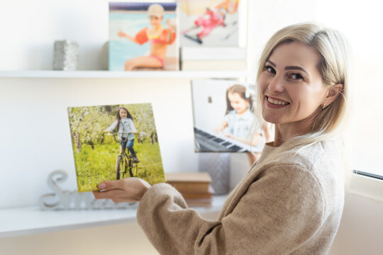 Young woman hanging a photo canvas painting on the wall