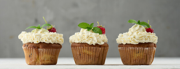 Baked cupcakes with white butter cream on the table, delicious dessert - obrazy, fototapety, plakaty