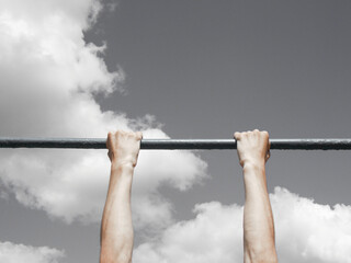 Pull-ups on the crossbar. Close-up. Hands against the sky