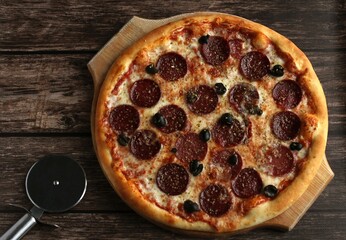 pepperoni pizza with sausage and olives on a dark wooden background