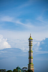 Obraz premium The mosque's domed minaret against the background of blue clouds