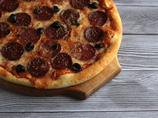 pepperoni pizza with salts and olives on a gray background
