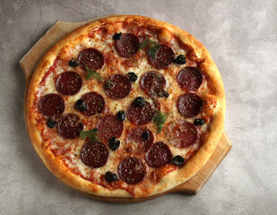 pepperoni pizza with salts and olives on a gray background