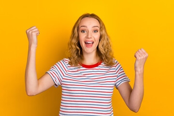 Portrait of shouting in winning with raised fists young girl wearing shirt clothes isolated on...