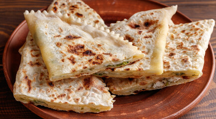 Delicious gourmet flat bread kutabs with herbs and cheese on a plate.