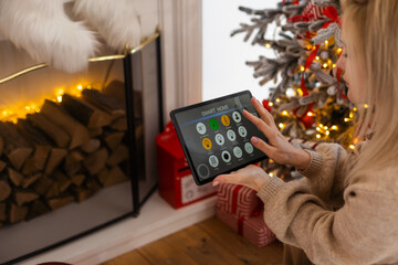 Young woman using application in his smart home at Christmas