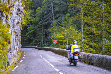 A motion blurred motorcyclist drives along a mountain road in nature