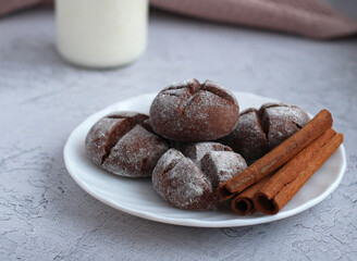 homemade round gingerbread with cinnamon in powdered sugar on a saucer with milk