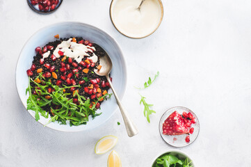 Healthy superfood, black lentil vegan salad with  arugula, parsley herb and pomegranate with tahini and  lemon dressing. Healthy vegan salad recipe concept, Atkins low carb diet, copy space - 548456306