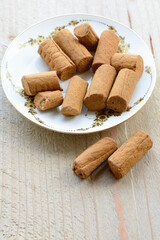Chocolate cookies are on the white plate on the wooden background. Brown biscuits in the morning on the wooden table