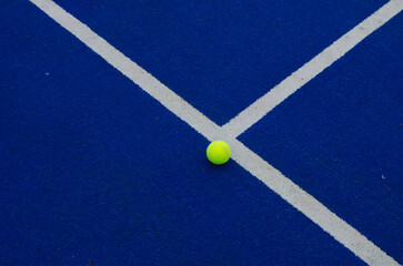 ball next to the line on a blue paddle tennis court