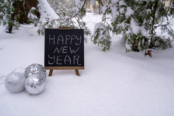 Happy new year wishes text inscription on blackboard. Silver balls baubles toy decorations....