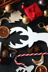 Small presents, various Christmas ornaments and deer figurine on dark background. Top view.