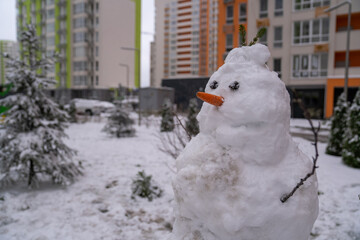 white snowman with carrot nose, made of snow, snowperson built in the backyard of residential...