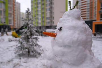 white snowman with carrot nose, made of snow, snowperson built in the backyard of residential...