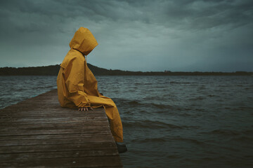 Mysterious hooded figure seated on a pier - 548459136