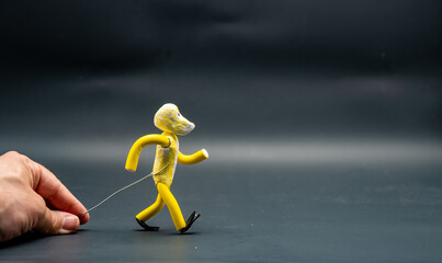 Stopmotion process of walking. First step. Man's hand holding with an aluminum wire a figure made with yellow modeling paste starting the process of walking. The 12 principles of animation.