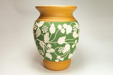 ceramic vase with floral carvings on a white background