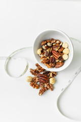 Close-up of a plate with different nuts and a centimeter tape. The concept of weight loss, healthy eating, overweight. Fitness menu.
