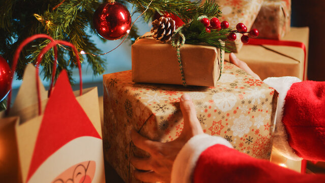 Santa Claus is placing the Christmas gift box under the tree
