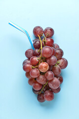 Composition with bunch of grapes and straw on color background