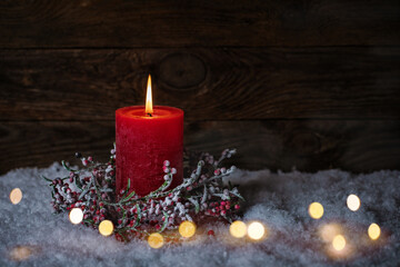 Christmas Candle with decoration in snow landscape with  magic lights. Copy space on dark wood...