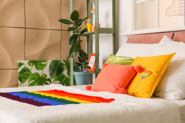 Comfortable bed with rainbow flags in room