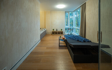 Modern interior of bedroom with lounge zone. Sunbeds. Coffee table. TV on wall. Panorama windows.