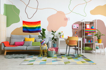 Interior of modern living room with stylish workplace, comfortable sofa and rainbow flags