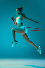 Young sportive girl in white sportswear training with sports expanders isolated over blue studio background in neon light. Run