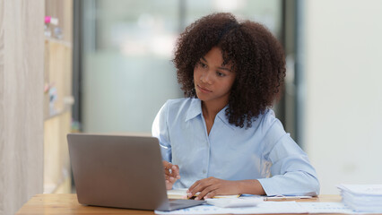 Fototapeta na wymiar Young African American businesswoman working by laptop at office, Focus at screen laptop, reading interesting article online and finance