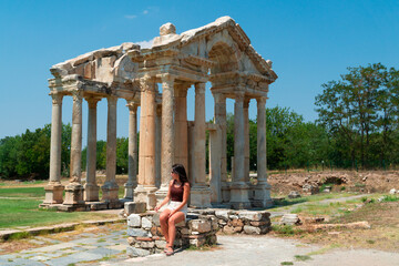 Young tourist sitting in front of the ruins of the temple of aphrodisia in turkey