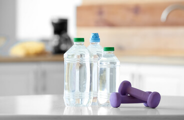 Bottles of water and dumbbells on table in kitchen