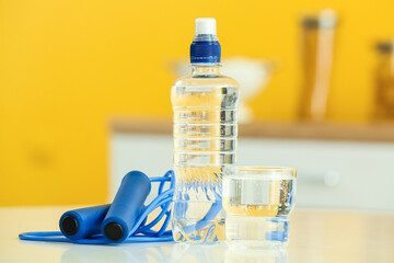 Bottle of water, glass and skipping rope on table in kitchen